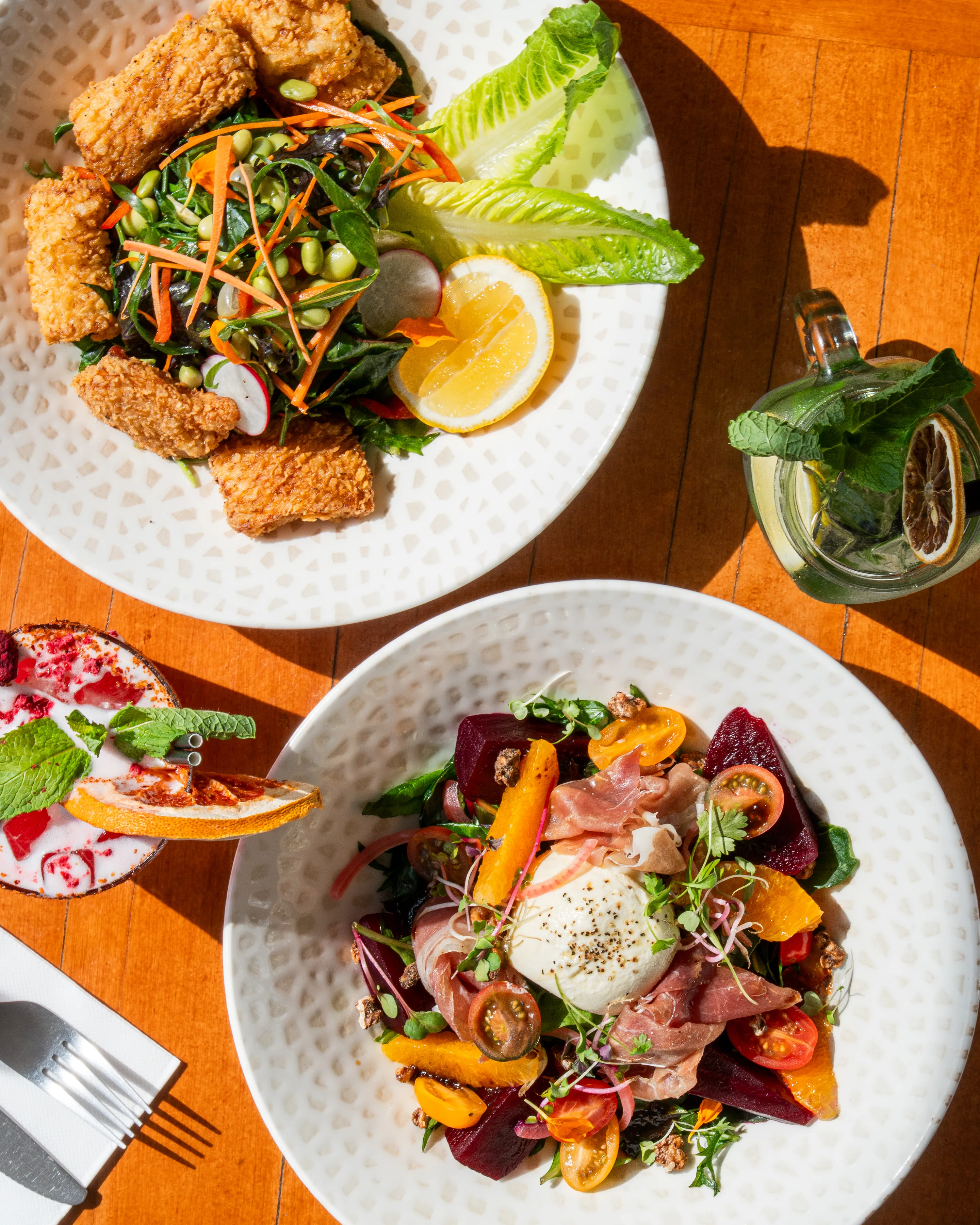 Food and cocktails on a sunlit table at Dolce